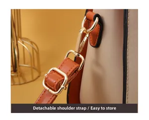 Detail of detachable shoulder strap with golden metal lobster clasp on beige leather handbag