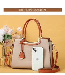 Size comparison of beige crocodile pattern handbag with a smartphone for scale