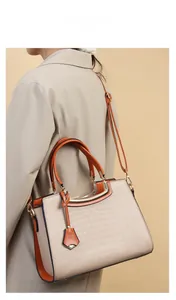 Model show of stylish beige crocodile pattern handbag with orange trim and gold hardware