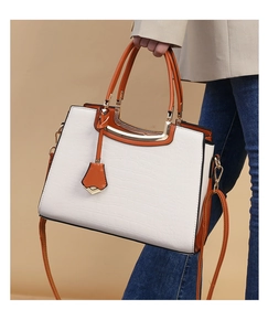 Detail of white and orange crocodile pattern handbag with gold clasp held by model