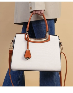 Detail of white crocodile texture handbag with orange trim and gold hardware accents