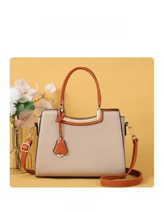 Close-up of beige crocodile pattern handbag with orange handles and metal hardware