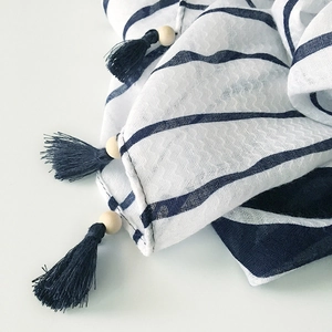 Detail of blue and white striped cotton linen scarf with wooden beads and navy tassels