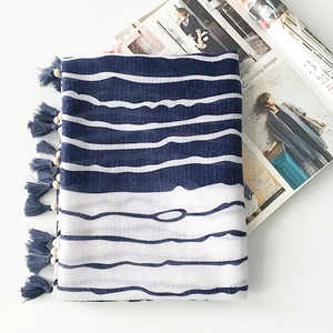 Detailed view of navy blue and white striped cotton scarf with wooden bead fringe tassels