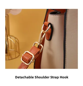 Detail of beige and orange leather bag showing gold hardware and detachable strap hook