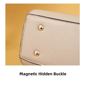 Detailed macro view showing the high-quality gold magnetic snap closures on the beige leather bag