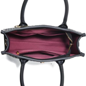 Detail shot of the spacious burgundy interior and gold zipper pocket of this black tote bag