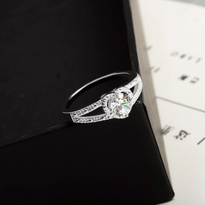Macro view of heart-shaped silver ring with round-cut center stone and double-split pavé band