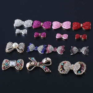 Detailed arrangement of crystal bow accessories and rhinestone pins on black background