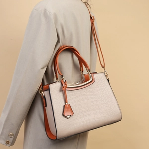 Chic beige and orange crocodile pattern handbag worn as a stylish shoulder bag