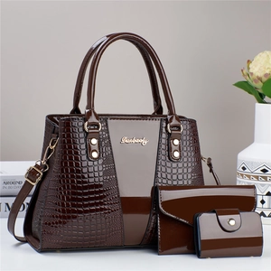 Detail view of deep brown patent leather handbag set with croc-embossed texture and metal logo