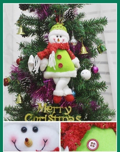 Macro details of a plush Christmas snowman ornament featuring green fabric and red scarf