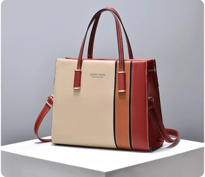Detail of color-block tote bag with beige, caramel, and red panels on a minimalist display