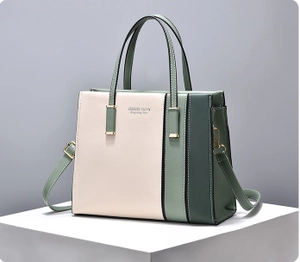 Detail view of tri-color stitching tote bag with gold hardware on a geometric stand