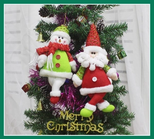 Close-up of Santa and Snowman plush ornaments hanging on a decorated Christmas tree