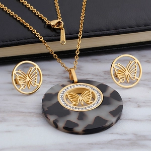 Golden butterfly necklace and earrings set with crystal inlay on marble surface