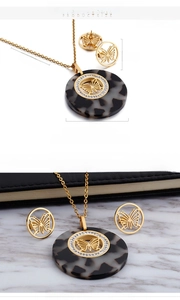 Detail view of gold butterfly jewelry set with dimensions and marble background