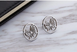 Macro view of silver hollow butterfly stud earrings on white marble background