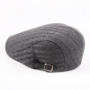 Casquette en tricot gris foncé avec torsades et boucle réglable sur fond blanc pur
