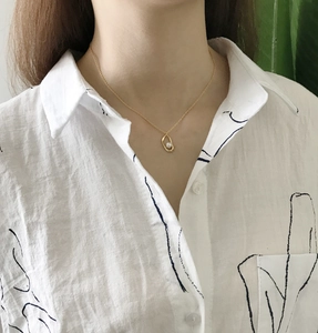 Close-up of a 925 sterling silver pearl necklace on a model with minimalist gold chain