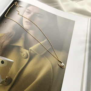 Detail of irregular gold ring pendant with pearl on a minimalist art book background