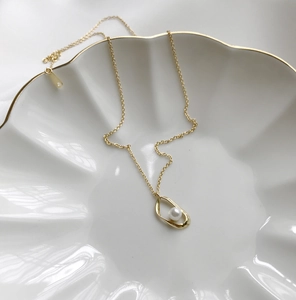 Detail of 925 sterling silver gold necklace with pearl pendant in shell ceramic tray