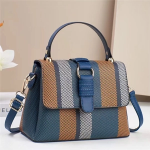Gewebte Tragetasche mit Kontrastfarben, blauem Lederriemen und goldenen Ringdetails
