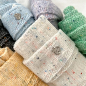Gros plan d'écharpes en tricot de laine colorées avec étiquettes métalliques en cœur