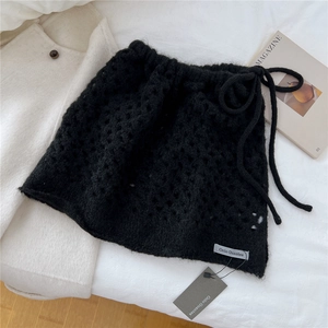 Dettaglio della gonna in maglia nera con trama a uncinetto e marchio Ocio Guantes