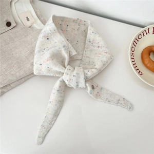 Détail d'une écharpe en maille de laine crème avec des points de couleur mouchetés