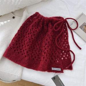 Dettaglio della gonna in maglia rosso scuro con coulisse regolabile in vita e trama crochet