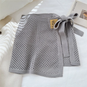 Detail eines grauen Strickwickelrockes mit seitlicher Schleife und Lochstrickmuster