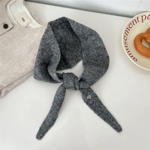 Détail d'une écharpe en laine mélangée grise avec pendentif cœur et texture tricotée