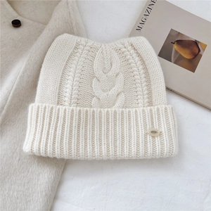 Détail d'un bonnet en laine beige avec oreilles de chat et revers sur fond minimaliste