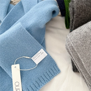 Close-up of 100% wool knitted scarf showing rib-knit edges and authentic wash label
