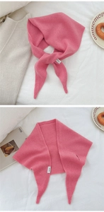 Dettaglio macro dell'etichetta 100% pura lana su una sciarpa a triangolo in maglia rosa