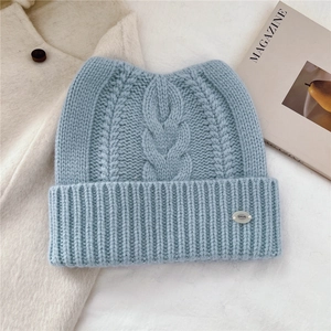 Détail du bonnet en maille bleu clair avec oreilles de chat et plaque argentée