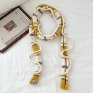 Close-up of striped knit scarf with yellow, green, and beige tones and brand label