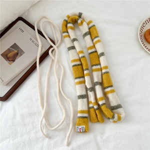 Detail of striped knitted scarf in yellow and cream with soft yarn texture and label