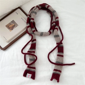 Close-up of striped knit narrow scarf texture with woven brand label on fabric