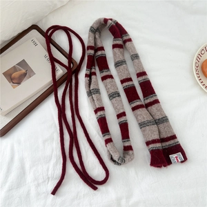 Detail of red and grey striped knit scarf showing soft texture and woven brand label