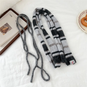 Detail of grey striped knit scarf and thin matching rope on soft white fabric background