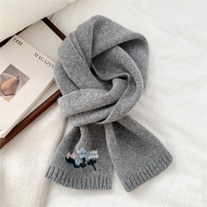 Close-up of grey knitted wool scarf featuring delicate floral embroidery and ribbed edges
