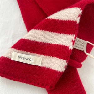 Detail of red and white striped knit scarf showing 100% wool texture and brand label