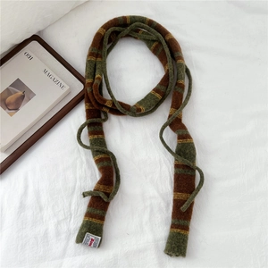 Detail of striped knit scarf in olive green and brown colors on white bedding