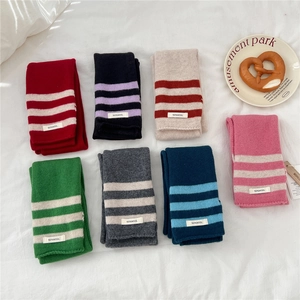 Flat lay of multiple colorful 100% wool striped knit scarves with soft fabric texture