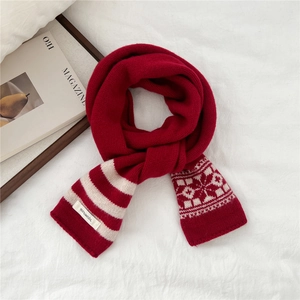 Close-up of a red and white knitted wool scarf with 100% wool label and snowflake patterns