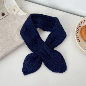 Close-up of navy blue knitted wool scarf with crossed bow design and cable textures
