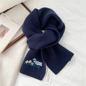 Detailed close-up of floral embroidery on a dark blue knitted wool scarf for winter
