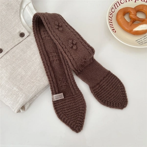 Detail of dark brown 100% wool knitted scarf with textured stitch and ball decor